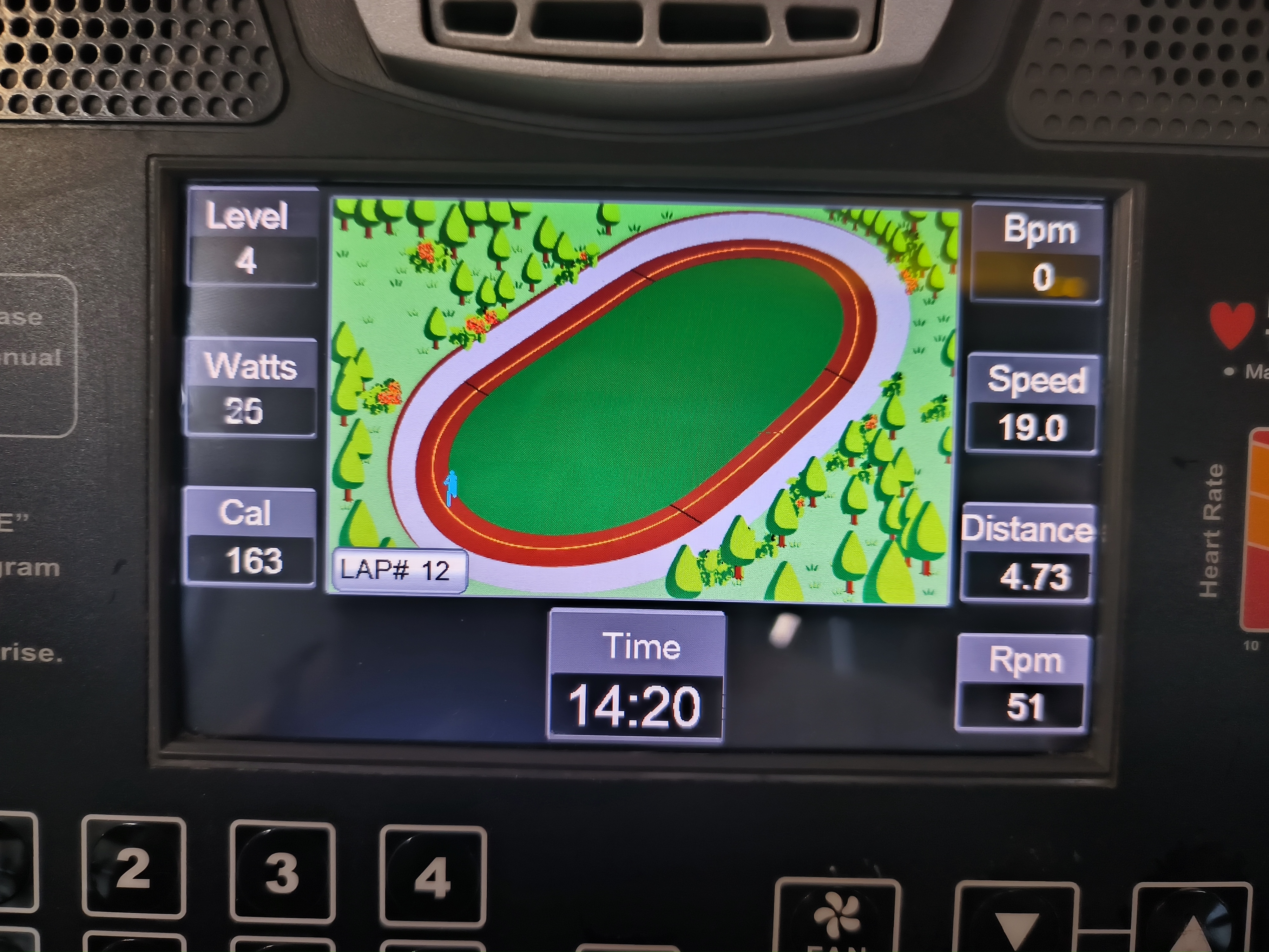 An image of a stationary cycling machine's interface, showing a virtual cyclist doing laps around a track.